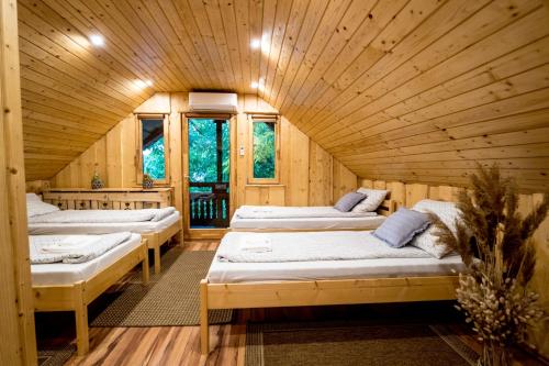 Una habitación con tres camas en una cabaña de madera. en Tündérkert Apartman, en Debrecen