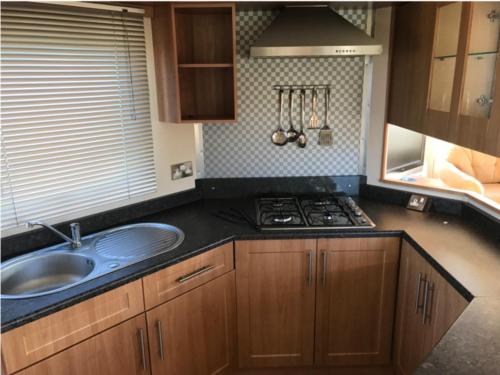 a kitchen with a sink and a stove at 2 bedroom static caravan on quiet park near Caernarfon & Snowdonia in Caernarfon