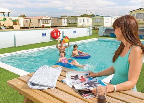 a woman sitting at a table in a swimming pool at 2 bedroom static caravan on quiet park near Caernarfon & Snowdonia in Caernarfon