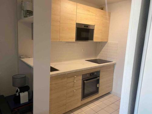 une cuisine avec des armoires en bois et un four à plaques de cuisson dans l'établissement Beach escape - bord de mer Port Argelès, à Argelès-sur-Mer