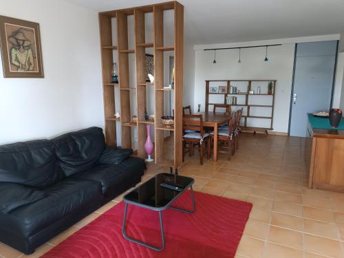 a living room with a black leather couch and a table at Appt Morne la Loge in Pointe-à-Pitre