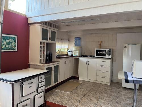 a large kitchen with white cabinets and a refrigerator at Casa Xixo Escultura in Gramado