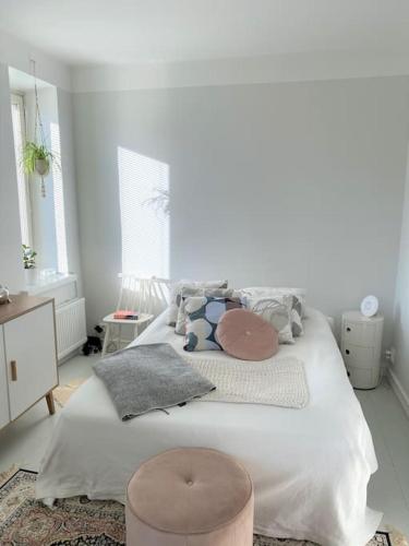 a white bedroom with a large bed and a stool at Valoisa ja täysin remontoitu huoneisto in Helsinki