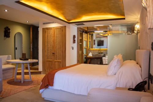 Hotel Boutique Casa Laja في سان ميغيل دي الليندي: غرفة نوم بسرير ابيض كبير وطاولة