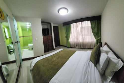 a bedroom with a large bed and a bathroom at Apartahotel Vincent Suites in Pasto