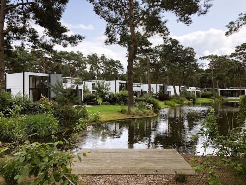 una casa con un estanque delante de ella en Delightful luxury 2-bedroom holiday home in nature, en Otterlo