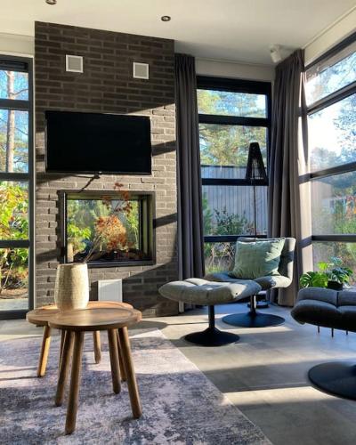 a living room with a fireplace and a tv at Delightful luxury 2-bedroom holiday home in nature in Otterlo