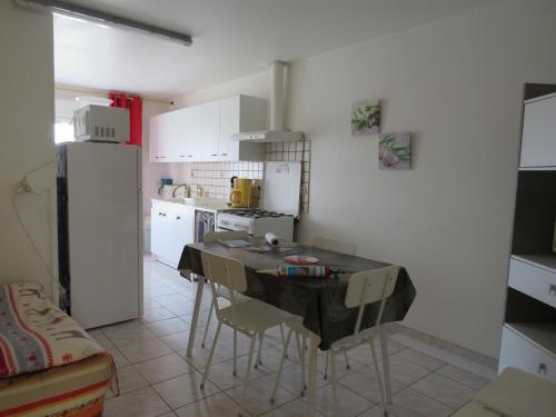 une cuisine avec une table, des chaises et un réfrigérateur dans l'établissement Gîte Orchidée, aux Herbiers