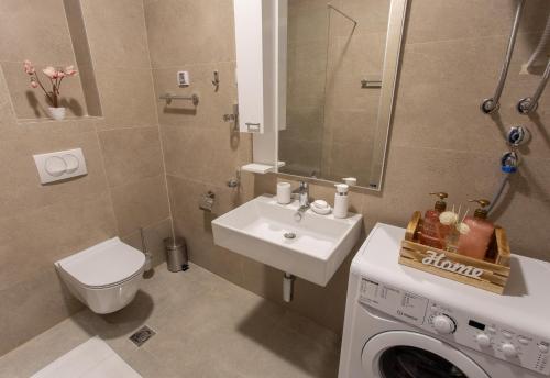 ein Badezimmer mit einem Waschbecken und einer Waschmaschine in der Unterkunft LINA - PG, Gorica Park View Apartment in Podgorica