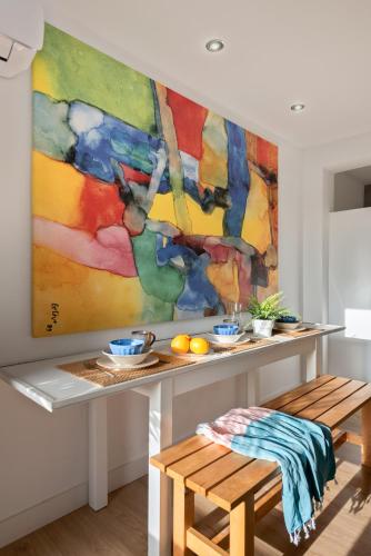 a painting hanging on a wall with a table and a bench at Apartamento Aljarafe in Valencina de la Concepción