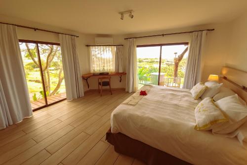 a bedroom with a large white bed and a balcony at Hotel Hare Uta in Hanga Roa
