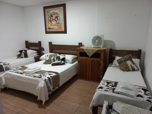 a room with three beds and a clock on the wall at Pousada Sinhá Moça Campos Ltda in São João del Rei