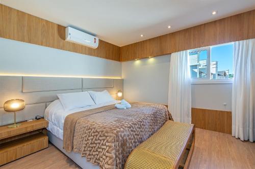 um pequeno quarto com uma cama e uma janela em Estação Canela - Stay House Temporada em Canela