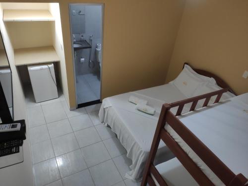 a room with two beds and a bathroom with a shower at Pousada Simão in Maragogi