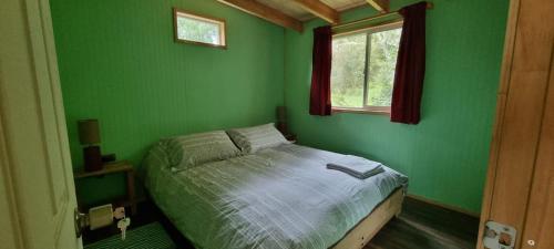 - une chambre verte avec un lit et une fenêtre dans l'établissement Cabañas Chucao Austral, à Puerto Montt