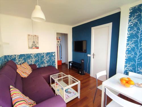 sala de estar con sofá púrpura y mesa en Beachfront Apartment ✓WiFi ✓Pool ✓SUP ✓Home Office, en Blanes