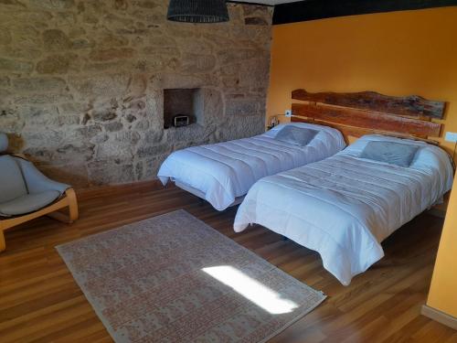 a bedroom with two beds and a stone wall at O fogar da musiña in Maside