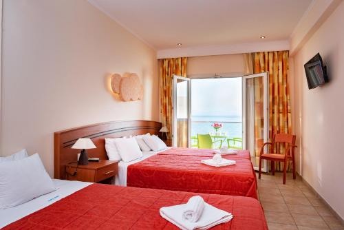 a hotel room with two beds and a balcony at Corfu Maris in Benitses