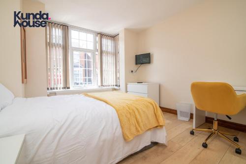 a white bedroom with a bed and a chair at Kunda House Dawlish in Birmingham