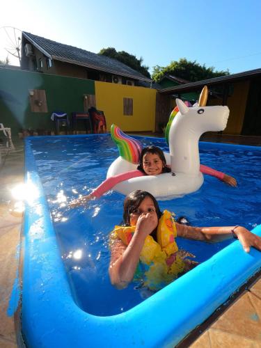 duas crianças a brincar numa piscina com um unicórnio insuflável em Rodrigo Hostel Suítes em Bonito