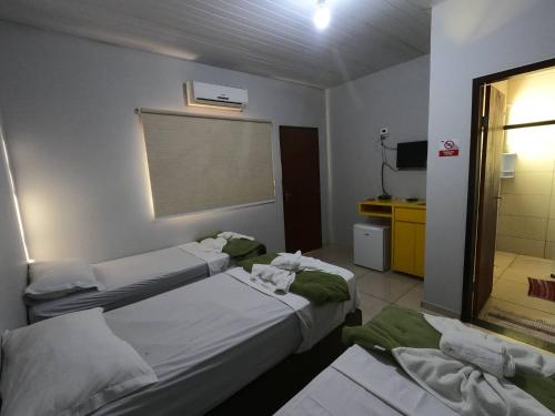 a hotel room with two beds and a bathroom at Rodrigo Hostel Suítes in Bonito