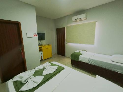 Cette chambre comprend deux lits et une télévision. dans l'établissement Rodrigo Hostel Suítes, à Bonito
