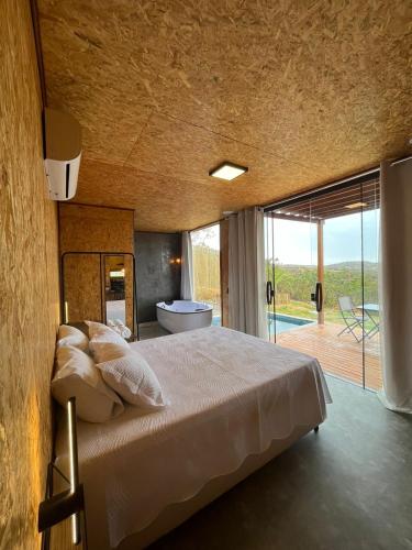 1 dormitorio con 1 cama y baño con bañera en Oka Vivah - Chale Oka da Montanha, en Jaboticatubas