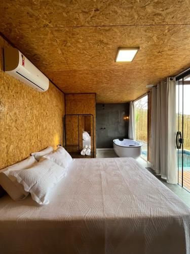 1 dormitorio con 1 cama grande y bañera en Oka Vivah - Chale Oka da Montanha, en Jaboticatubas