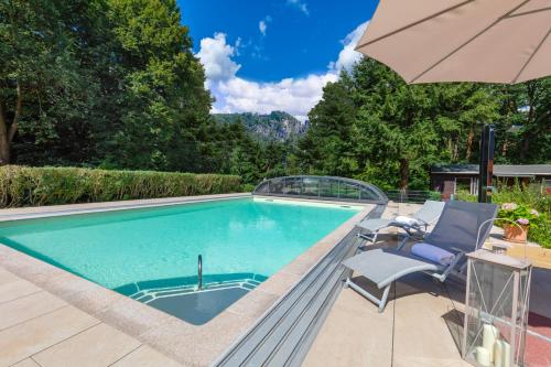 einen Pool mit einem Stuhl und einem Sonnenschirm in der Unterkunft Laasenhof Resort in Struppen