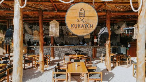 a restaurant with wooden tables and chairs and a sign at Aldea Kuká, Luxury Eco Boutique Hotel - Adults Only in Holbox Island