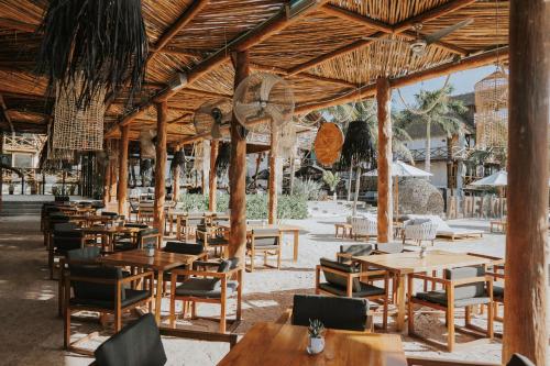 um restaurante vazio com mesas e cadeiras de madeira em Aldea Kuká, Luxury Eco Boutique Hotel em Ilha Holbox