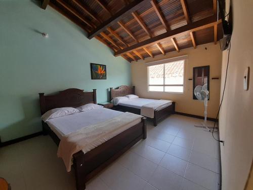 1 dormitorio con 2 camas y ventana en HOSTAL HELICONIAS, en Charalá