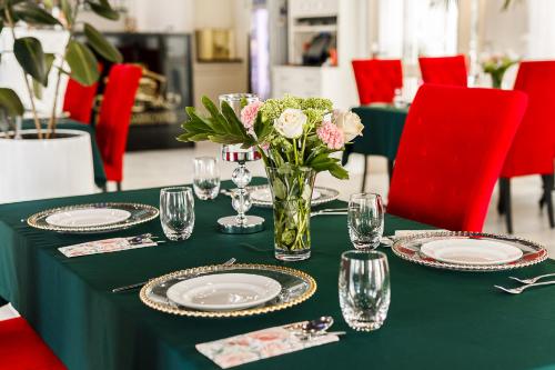 a green table with plates and a vase of flowers at PALAC DABROWKA in Rawicz