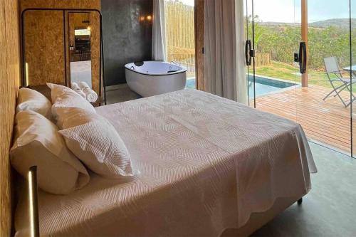 a bedroom with a large bed with a tub and a bath tub at OKA VIVAH - Chalé Oka da Montanha in Jaboticatubas