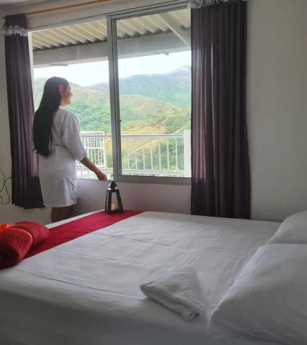 Una mujer mirando por una ventana en una cama en MIRADORES D ALESSANDRA en Pueblo Bello