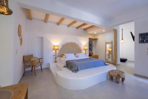 a white bedroom with a large bed and a table at Infinity Blue Suites & Spa in Astypalaia Town