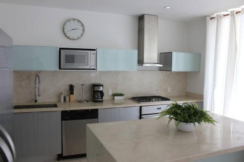 a kitchen with white appliances and a clock on the wall at Casa Moderna Fresca and The PoolClub at Mahogany Bay! in San Pedro