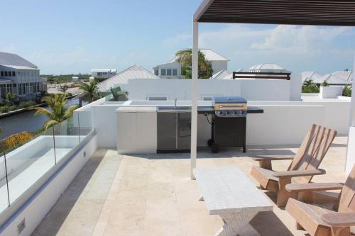 a patio with a grill on the roof of a house at Casa Moderna Fresca and The PoolClub at Mahogany Bay! in San Pedro
