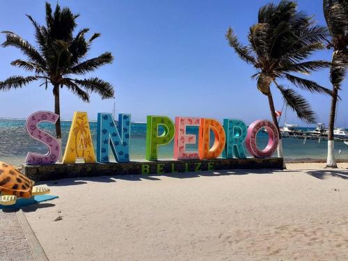 a sign on a beach with palm trees and the ocean at Casa Moderna Fresca and The PoolClub at Mahogany Bay! in San Pedro