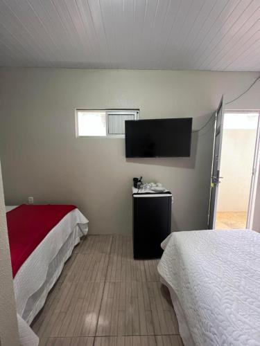 a bedroom with two beds and a flat screen tv at Pousada da Celma in Fortaleza