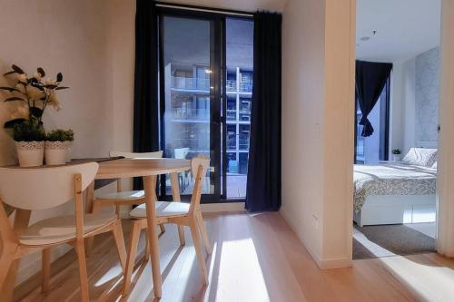 a dining room with a table and chairs and a bedroom at Cozy 1BR Apartment in the heart of Canberra in Canberra