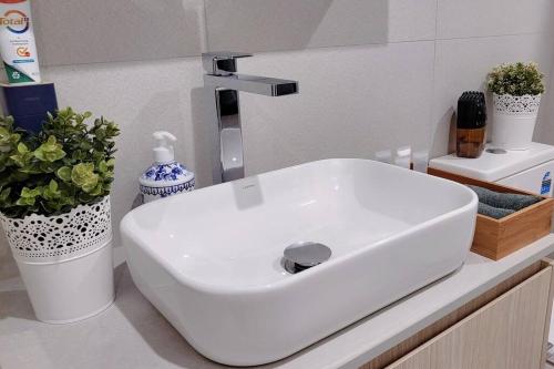 a white sink in a bathroom with plants at Cozy 1BR Apartment in the heart of Canberra in Canberra