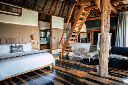 1 dormitorio con cama, escalera y silla en Aldea Kuká, Luxury Eco Boutique Hotel, en Isla Holbox