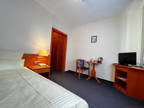 um quarto de hotel com uma cama e uma secretária com uma televisão em Hotel Zur Stadt Cassel em Neukirchen