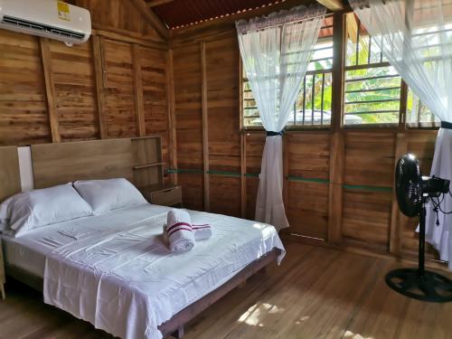 ein Schlafzimmer mit einem Bett in einem Holzzimmer in der Unterkunft Cabañas Estrella de Mar, Palmar del viento, Moñitos in Moñitos