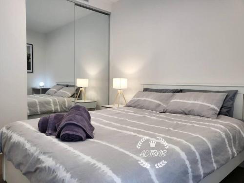 um quarto com uma cama grande e toalhas roxas em Modern new 1-bedroom apartment in Canberra City em Camberra
