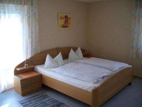 uma cama com lençóis brancos e almofadas num quarto em Gasthaus Krone em Pforzheim