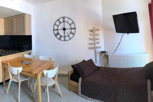 een woonkamer met een tafel en een klok aan de muur bij Beau Studio La Mongie Tourmalet Pic du Midi in La Mongie