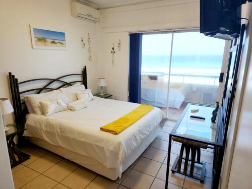 een slaapkamer met een bed en een groot raam bij Beachside 3 bed apartment with stunning seaviews in Amanzimtoti