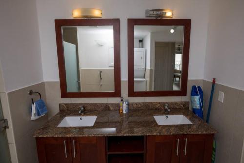 a bathroom with two sinks and two mirrors at Sand Bar Condo - 1BR Suite next to The Morgan Resort in Maho Reef
